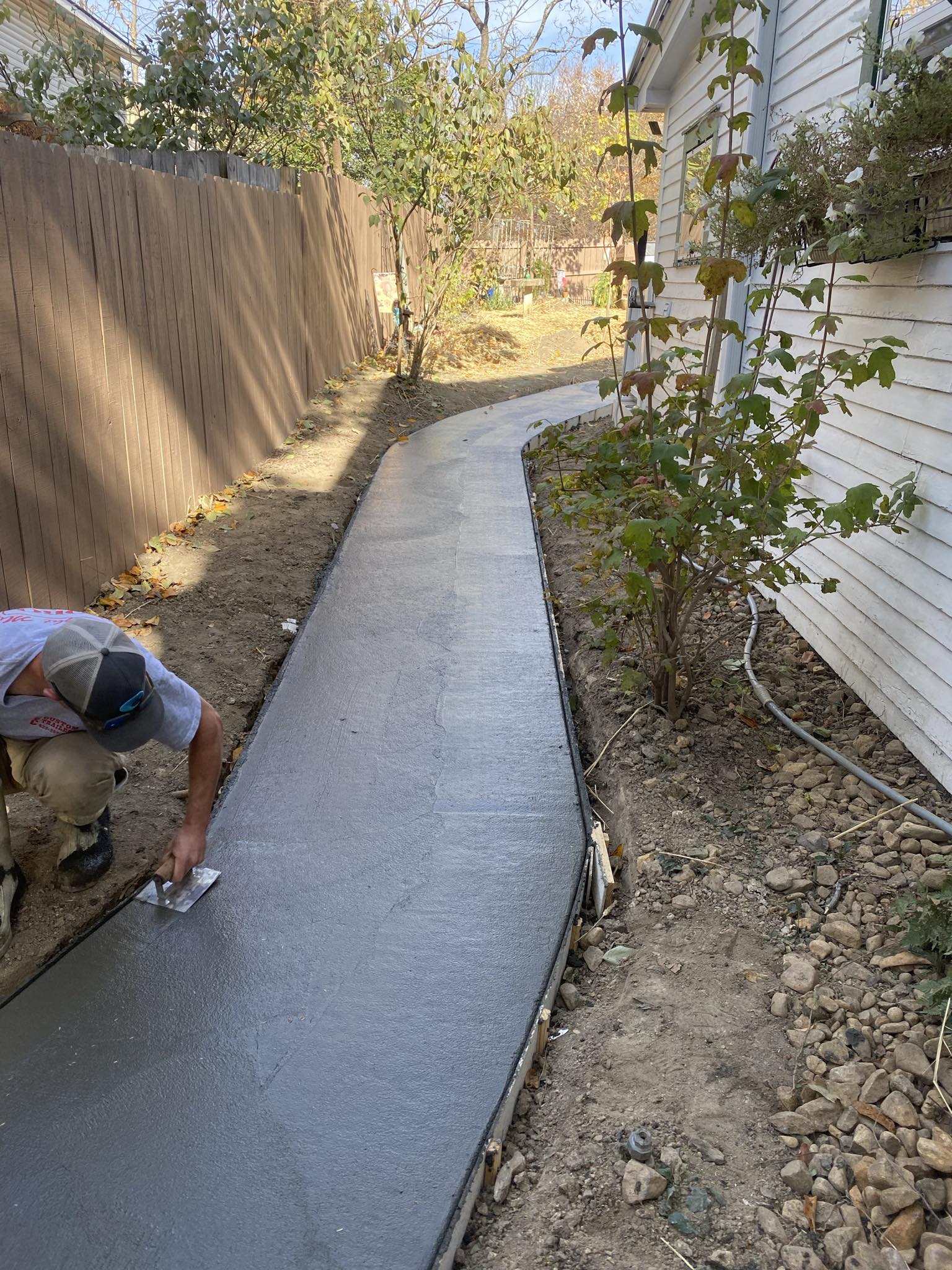 Crew member finishing a freshly poured concrete walkway