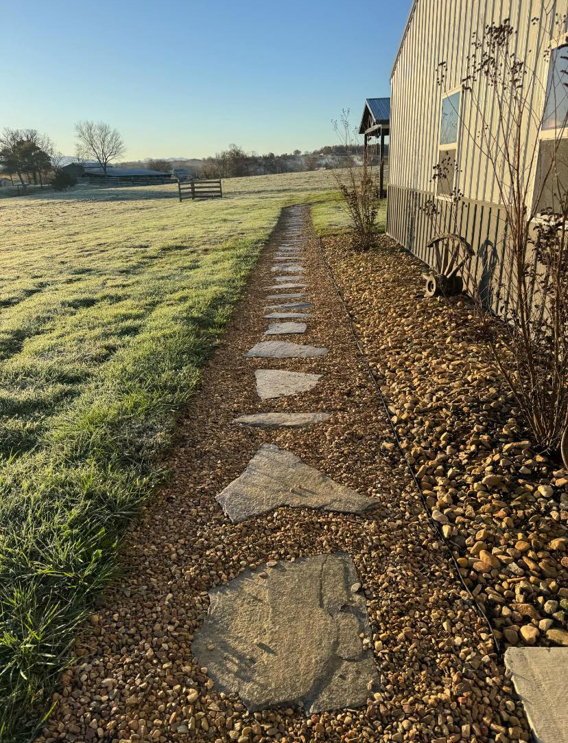 Fieldstone stepping path through a gravel bed beside a barn